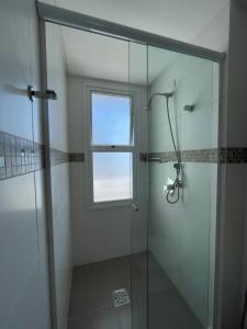 a bathroom with a glass shower with a window at Apartamento espetacular, melhor vista e localização de Torres in Torres