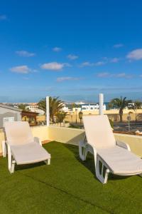 dos sillas blancas sentadas en el césped en el techo en Private villa with heated pool & terrace see view, en Corralejo