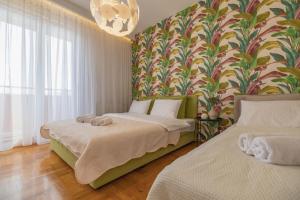 a bedroom with two beds and a floral wallpaper at Apartment Simpatico in Novi Sad