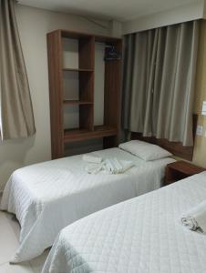 two beds in a hotel room with white sheets at Pousada Casarão do Porto - Porto de Galinhas PE in Porto De Galinhas