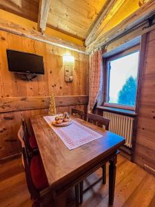 een eetkamer met een houten tafel en een televisie bij La Buca delle Fate in Gressan