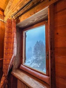 een raam in een kamer met uitzicht op een met sneeuw bedekte boom bij La Buca delle Fate in Gressan