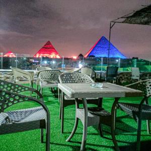 een tafel en stoelen op een dak met piramides bij Happy days Pyramids Inn in Caïro
