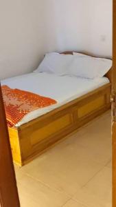 a wooden bed with white sheets and pillows on it at Villa Valentine in Bana