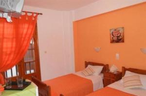 1 Schlafzimmer mit 2 Betten mit orangefarbenen Wänden und einem Fenster in der Unterkunft nostalgo in Skiathos-Stadt