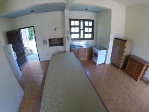 a kitchen with a counter and a refrigerator in it at Suítes Casa Amarela da Ferrugem in Garopaba