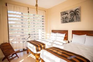 a bedroom with two beds and a window at Hotel Santa Cruz Punta Zicatela in Puerto Escondido