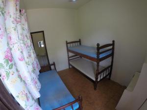 a small room with two beds and a curtain at Suítes Casa Amarela da Ferrugem in Garopaba
