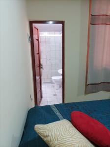 a bedroom with a bed and a bathroom with a toilet at Hotel Apartamentos "Dominó" in Tarija