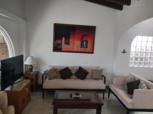 a living room with a couch and a tv at Aventura Pacifico Boutique Hotel in Bucerías
