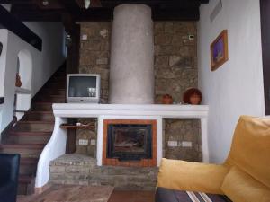 sala de estar con chimenea de piedra y TV en CASA HUGANA, en Benalup-Casas Viejas