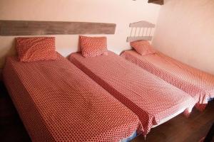 drie bedden in een kamer met rode netten erop bij CASA HUGANA in Benalup Casas Viejas