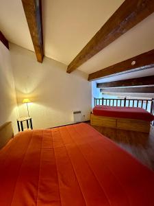 a room with a large wooden table and a red bed at LE MONTAGNARD in Isola 2000
