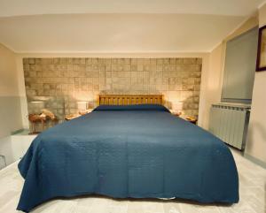 a large blue bed in a room with two lamps at Vermaaten Boutique Suites Diamond in Todi