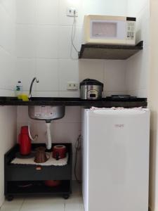 a small kitchen with a microwave and a refrigerator at Boa Vida Ubatuba in Ubatuba