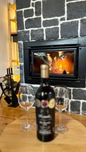 a bottle of wine and two glasses on a table in front of a fireplace at Apartment 533 at Aparthotel Vucko Jahorina in Jahorina