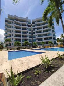 un hôtel avec une piscine en face d'un bâtiment dans l'établissement Acogedor apartamento con vista al mar en coveñas, à Coveñas