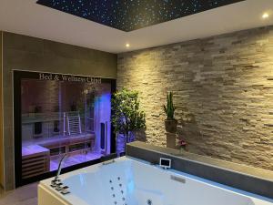 a bath tub in a room with a brick wall at Bed & Wellness Chinel Luxe vakantiehuis met Sauna's en Bubbelbad in Sint Annaland