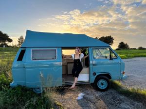 Rent a BlueClassics 's campervan vw T3 in Algarve au Portugal, في بورتيماو: امرأة تقف في الجزء الخلفي من فان أزرق
