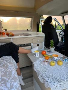 Rent a BlueClassics 's campervan vw T3 in Algarve au Portugal, في بورتيماو: شخص يجلس في سيارة أجرة مع طاولة مع طعام