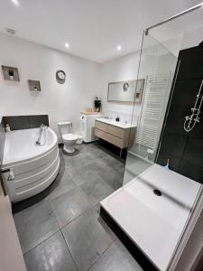La salle de bains est pourvue d'une baignoire, de toilettes et d'un lavabo. dans l'établissement Maison plein cœur de Rosendael, à Dunkerque
