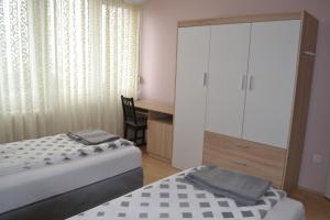 a bedroom with two beds and a desk and a window at Sweet Dreams Apartman in Nyíregyháza