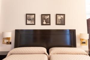 a bedroom with a headboard and three pictures on the wall at Hostal Plaza in Marmolejo