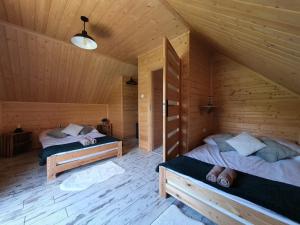two beds in a room with wooden walls at Młynówka Domek przy Młynie in Krościenko