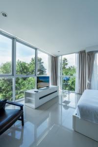 a white bedroom with a bed and a large window at Chic Condominium by Redfox Hospitality in Karon Beach