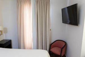een hotelkamer met een bed, een stoel en een televisie bij Hostal Plaza in Marmolejo