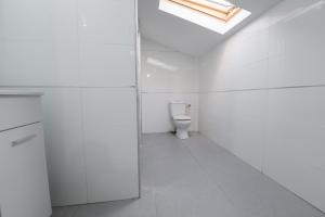 a white bathroom with a toilet and a skylight at Luxury studio 5 min from beach in Rishon LeẔiyyon