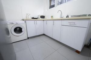eine weiße Küche mit einer Waschmaschine und einem Waschbecken in der Unterkunft Luxury studio 5 min from beach in Rischon LeZion
