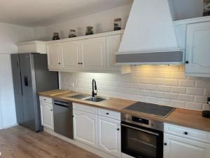 a kitchen with white cabinets and a sink and a stove at *NEU* Extravagantes Eifelhaus am Nürburgring in Mannebach