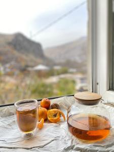 un pot en verre de thé et quelques oranges sur une table dans l'établissement Sargsyans guest hause, à Bjni