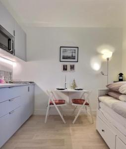 een kleine witte keuken met een tafel en een bed bij Studio confort Vanves Paris Porte de Versailles in Vanves