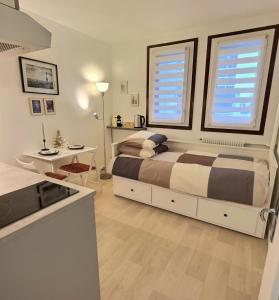 a bedroom with a bed and a table and two windows at Studio confort Vanves Paris Porte de Versailles in Vanves