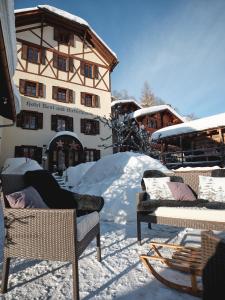 einen schneebedeckten Hof mit Stühlen und einem Gebäude in der Unterkunft Hotel Nest- und Bietschhorn in Blatten im Lötschental