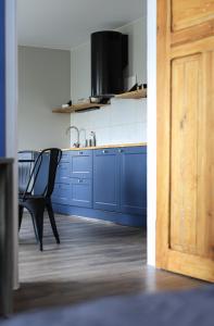 a kitchen with blue cabinets and a black chair at Sea Zone Apartament przy parku in Wejherowo