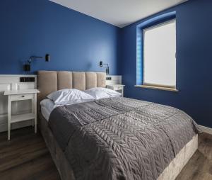 a blue bedroom with a large bed and a window at Sea Zone Apartament przy parku in Wejherowo