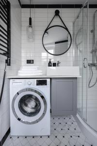 a white bathroom with a washing machine and a sink at Sea Zone Apartament przy parku in Wejherowo