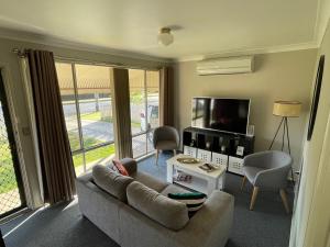 a living room with a couch and a tv at Comfortable 2-Bedroom home in Mudgee - Rest Easy Mudgee in Mudgee