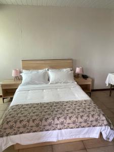 een slaapkamer met een groot wit bed met 2 lampen bij Kirin Guesthouse and Restaurant in Port Louis
