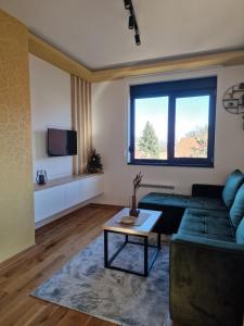 a living room with a green couch and a table at Hedonist Zlatibor Mountain Wellness & SPA in Zlatibor