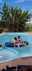 three people are riding on a raft in a swimming pool at Pousada Legal in Chapecó