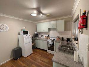 a kitchen with a white refrigerator and a sink at Comfortable 2-Bedroom home in Mudgee - Rest Easy Mudgee in Mudgee