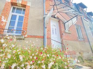 uma casa com uma porta branca e algumas flores em Coeur de Sologne, la Loire et les châteaux. em Dhuizon