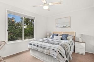 a white bedroom with a bed and a window at Bayview Cottage in Ventnor