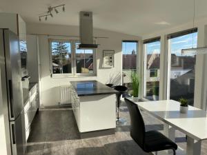 a kitchen with a white island and a table at Cozy Apartment next Outlet Center & Airport with Pool & Garden in Parndorf