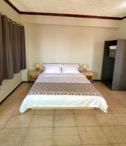 een slaapkamer met een groot bed met 2 nachtkastjes bij Kirin Guesthouse and Restaurant in Port Louis