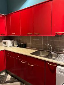 a kitchen with red cabinets and a sink at 1 bedroom flat in Kings cross! London in London